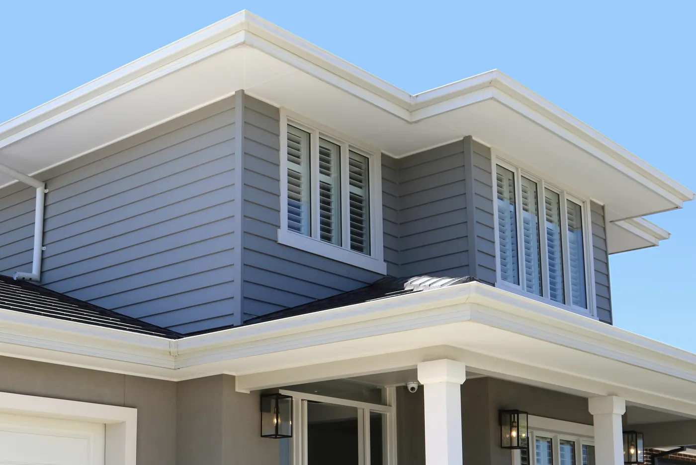 A two-storey weatherboard home with white trim and plantation shutters