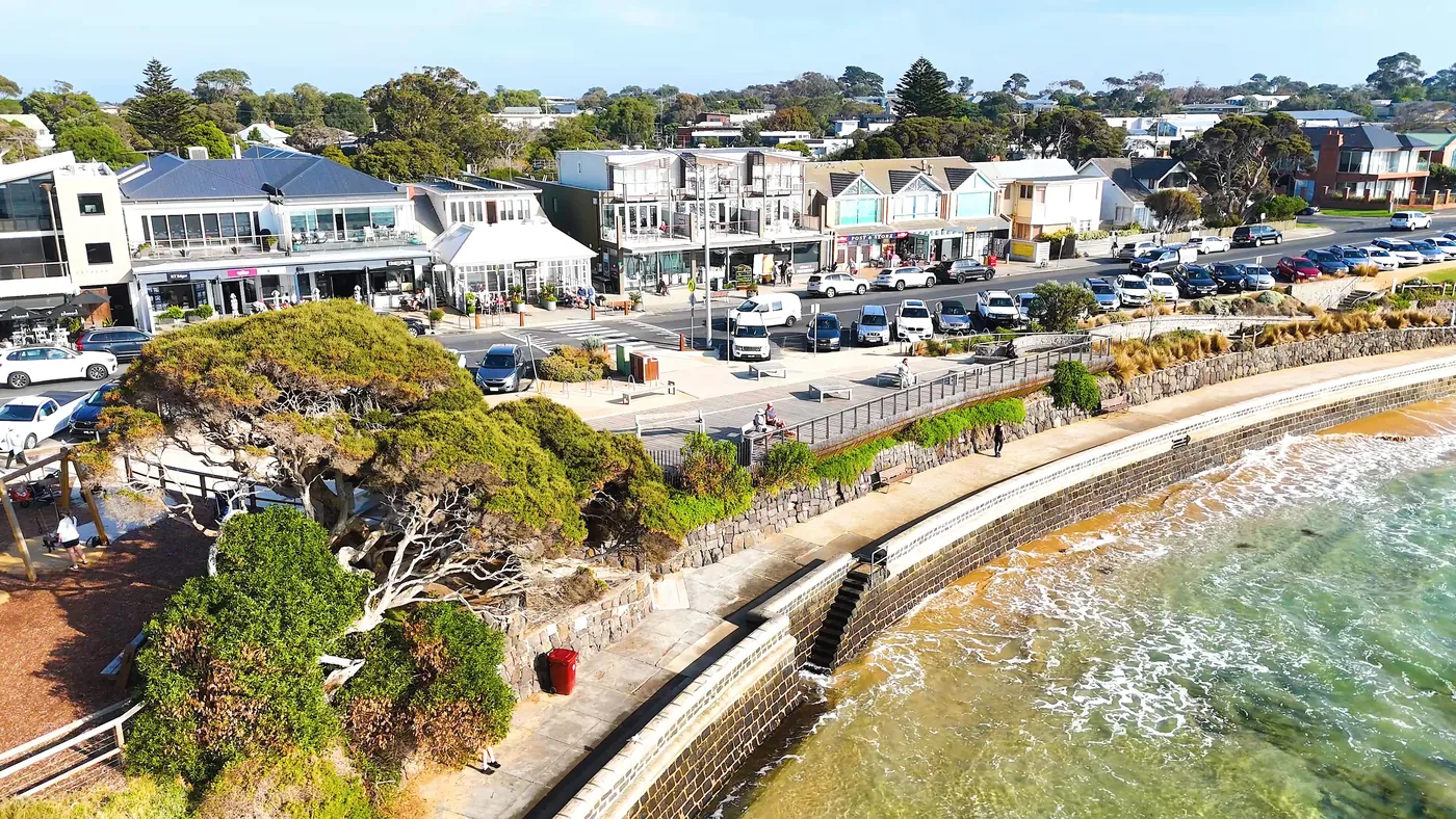 Seaside homes above a sandy shoreline, seen from the air