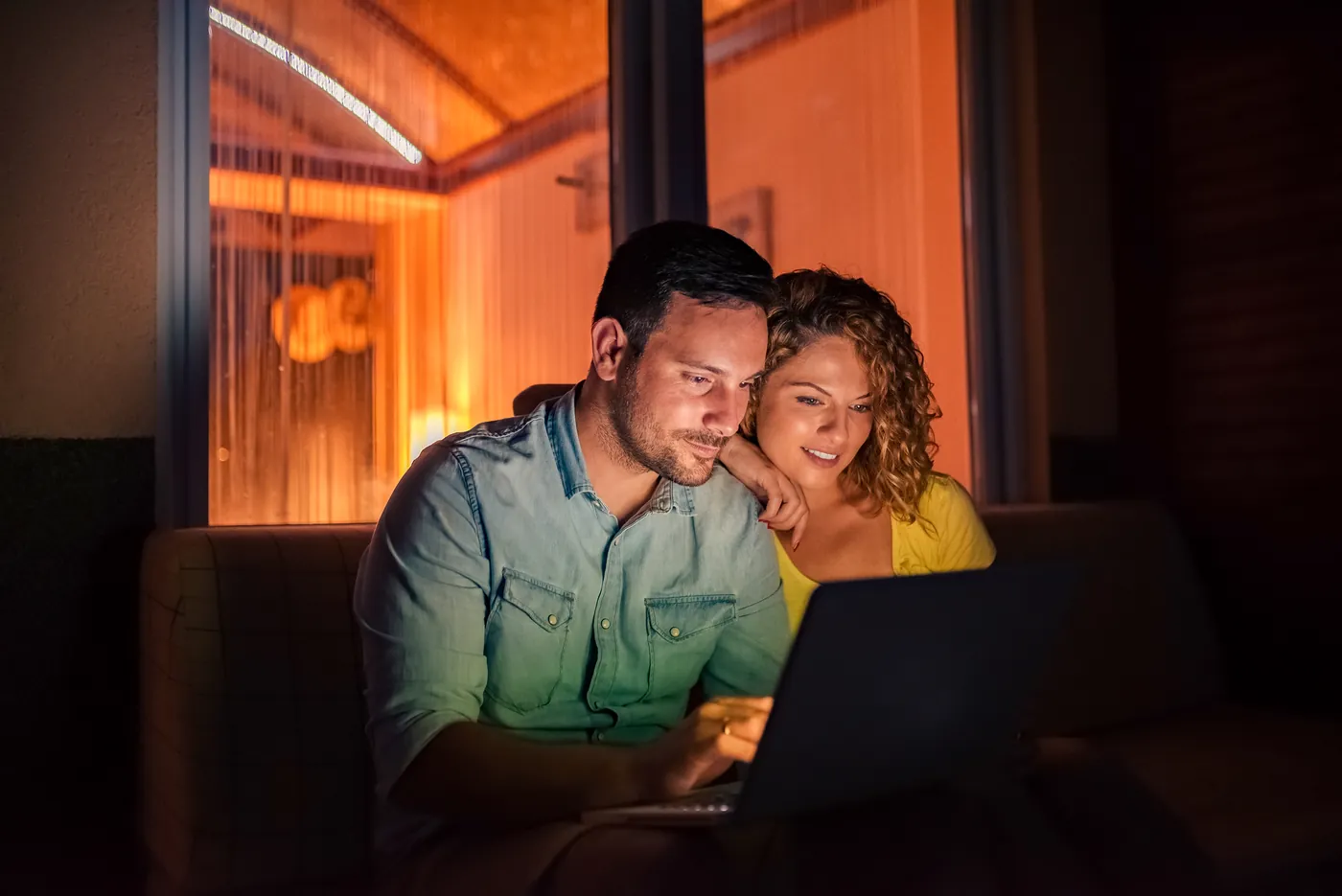 A couple looking at a laptop together in the evening